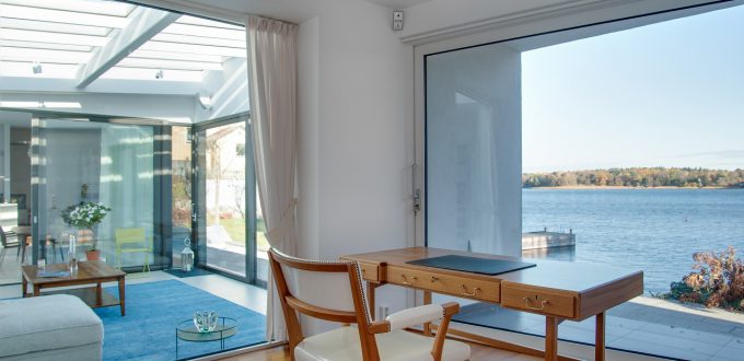 A luxury beach house with glass windows and the beautiful scenery of the sea in the background