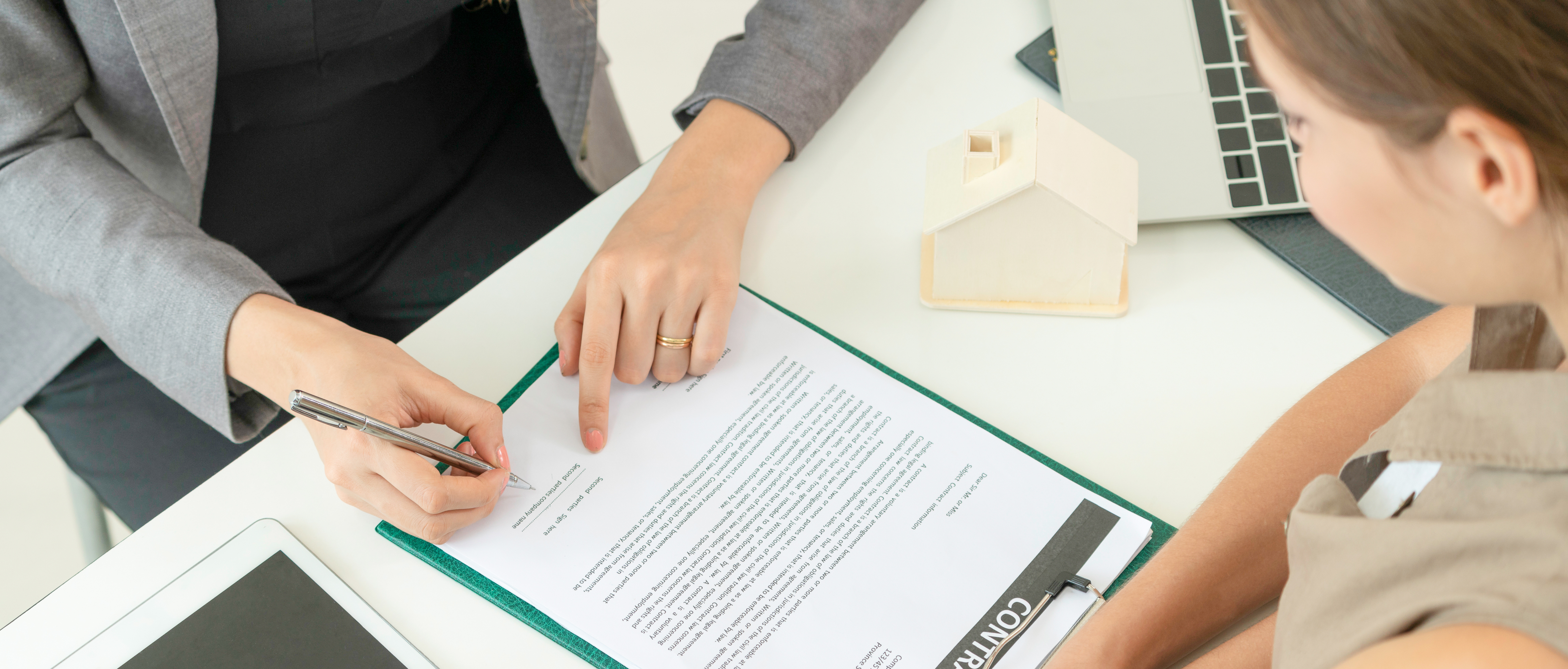 Client signs document regarding real estate activity next to lawyer or real estate agent sitting at office desk. Business concept of selling and buying house.