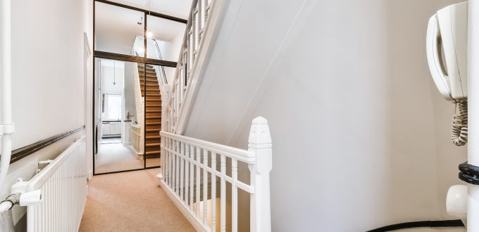 Residential house second floor with staircase and white fence against mirrored sliders of closet